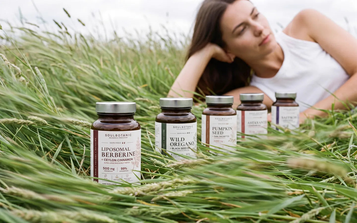 Cinq formules dans une prairie d'été, une femme allongée dans l'herbe derrière elles